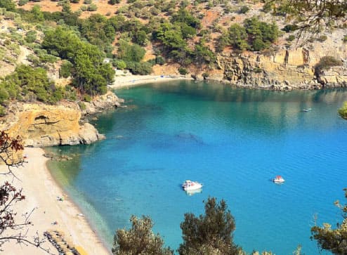 Secluded rocky cove with deep blue water and a boat anchored in Thassos