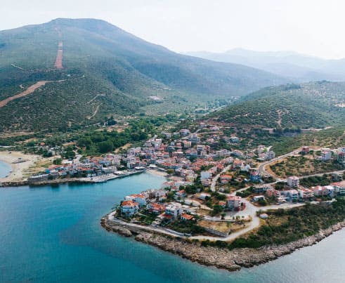 Drone view of a small Thassos harbour village nestled between green mountains